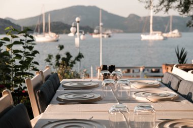 Sahil kenarındaki restoranda servis masası, beyaz ve mavi renkler, gün batımı saati, Seaview 'da akşam yemeği.