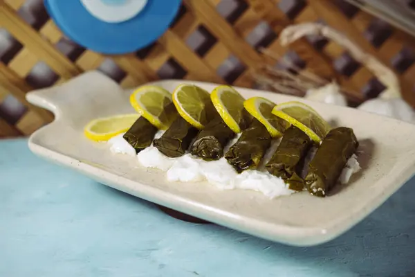 stock image dolma or dolmades greek and turkish national food of stuffed vine grape leaves rolls ooked in olive oil served on blue background with youghurt and lemons