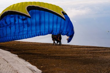 Yamaç paraşütü pilotu iniş için hazırlanıyor. Açık kanatlarla, turistler için popüler bir ekstrem spor aktivitesi.