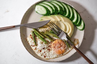 Sabah kahvaltısı, günlük hızlı sağlıklı pişirme, kuşkonmaz, yumurta, salatalık, kızarmış ekmek, beyaz mutfak arka planında avokado.
