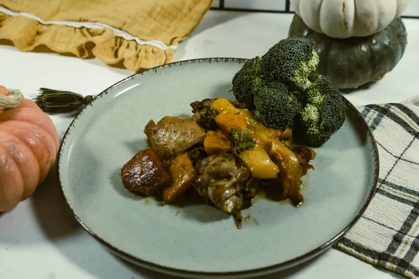 stock image chicken meat saute stewed with pumpkin and fresh broccoli, served with yellow kitchen cloth napkin and decorative mini pumpkins, autumn  season menu