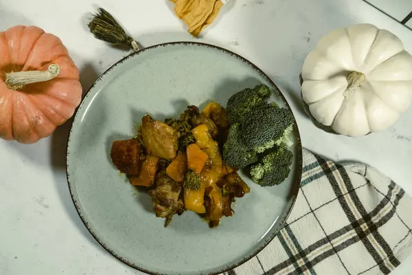 stock image chicken meat saute stewed with pumpkin and fresh broccoli, served with yellow kitchen cloth napkin and decorative mini pumpkins, autumn  season menu