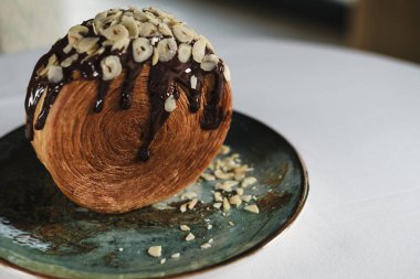 New York Roll, çikolatalı kruvasan hamur hamuru, içinde kremalı, seramik çağdaş tabakta servis edilen kristal desenli, fındık ve fındıklı.