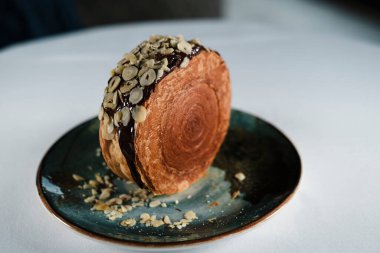 New York Roll, çikolatalı kruvasan hamur hamuru, içinde kremalı, seramik çağdaş tabakta servis edilen kristal desenli, fındık ve fındıklı.