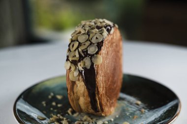 New York Roll, çikolatalı kruvasan hamur hamuru, içinde kremalı, seramik çağdaş tabakta servis edilen kristal desenli, fındık ve fındıklı.