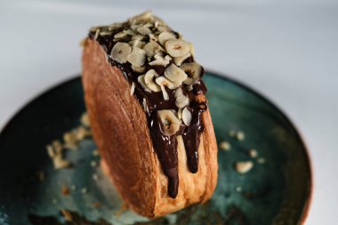 New York Roll, çikolatalı kruvasan hamur hamuru, içinde kremalı, seramik çağdaş tabakta servis edilen kristal desenli, fındık ve fındıklı.