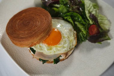 New York usulü sandviç, kruvasan hamurlu, füme somon, avokado, çırpılmış yumurta veya taze yeşillikli omlet.