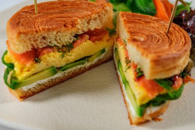New York usulü sandviç, kruvasan hamurlu, füme somon, avokado, çırpılmış yumurta veya taze yeşillikli omlet.