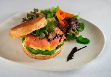 New York usulü sandviç, kruvasan hamurlu, füme somon, avokado, çırpılmış yumurta veya taze yeşillikli omlet.