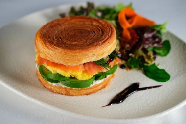 New York usulü sandviç, kruvasan hamurlu, füme somon, avokado, çırpılmış yumurta veya taze yeşillikli omlet.