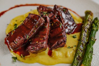 Kırmızı şarap soslu fileto. Patates püresi, soğan, ızgara kuşkonmaz, beyaz tabak ve arka plan.