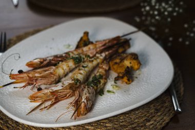 Köy restoranında mantarla servis edilen sarımsak soslu ızgara karides ve beyaz şarap, gerçek hayat yemeği konsepti.