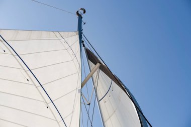 Direkte açık yelkenler, yelkenlinin altından manzara, aydınlatma çubukları, arama ışığı, derin mavi gökyüzü.