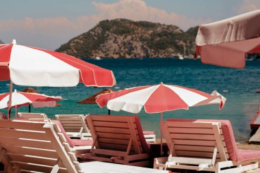 Plaj kulübünde güneşli ve rüzgarlı bir günde pembe şemsiyeli ve güneşli yaz havası, Türk Rivierası 'nın inanılmaz doğası.