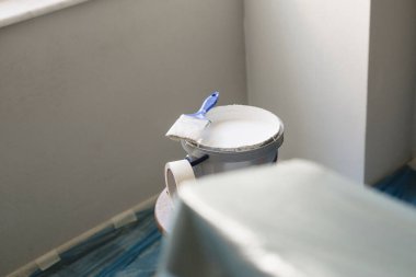 Beyaz boya ve fırça kutusu, evde duvarları boyamaya hazır bant.