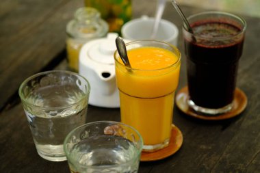 Serinletici soğuk içecekler. Mango suyu, dut suyu, kahverengi ahşap masadaki su..
