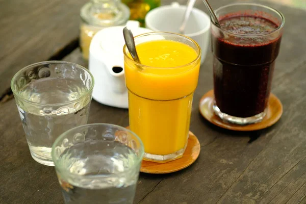 refreshing cold drinks. Mango juice, mulberry juice, water on a brown wooden table.