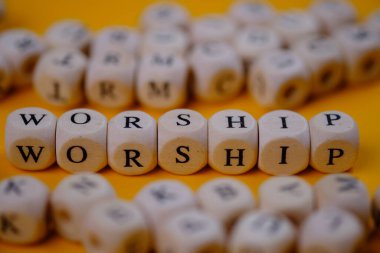 worship concept on wooden cubes blocks on yellow background 