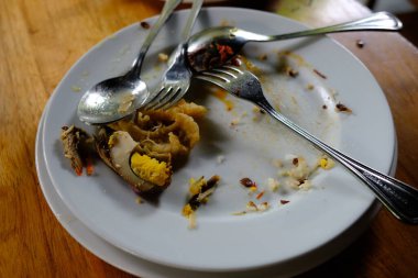 piles of dirty plates, spoons, forks, and leftovers in a restaurant. Leftover unprocessed food is a health problem for humans. while in other parts of the world there is a problem of hunger 