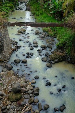 River in valley-shaped mountainous areas, with large rocks and murky water. Landscape in Indonesia. Tropical paradise. Rocky river.