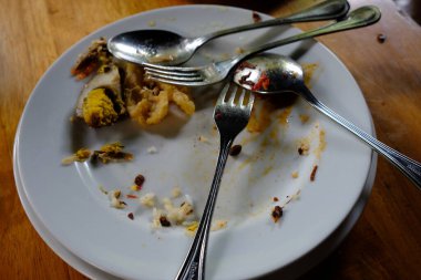 piles of dirty plates, spoons, forks, and leftovers in a restaurant. Leftover unprocessed food is a health problem for humans. while in other parts of the world there is a problem of hunger 