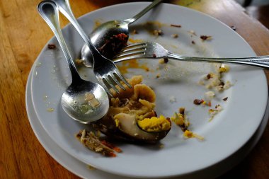 piles of dirty plates, spoons, forks, and leftovers in a restaurant. Leftover unprocessed food is a health problem for humans. while in other parts of the world there is a problem of hunger 