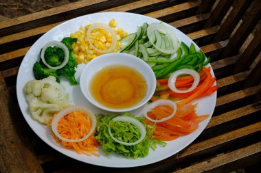 salad plate consisting of sliced vegetables with a salad dressing of honey and mustard