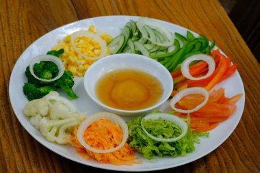 salad plate consisting of sliced vegetables with a salad dressing of honey and mustard