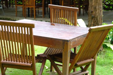 Boş ahşap masa ve bahçede sandalyeler.