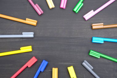 multi colored markers on a black background. top view