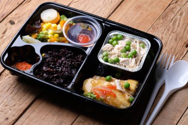 Black rice, yellow tofu, savory chicken, stir-fried pumpkin and chickpeas, and fruit pudding in container