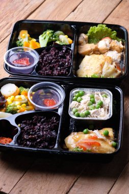 Black rice, yellow tofu, savory chicken, stir-fried pumpkin and chickpeas, and fruit pudding in container