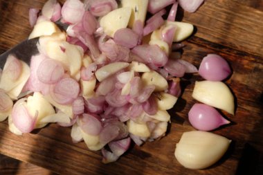 Sliced onion and garlic on a wooden cutting board