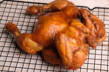 Ayam Panggang. Whole roasted chicken with soy sauce and spices. on the cooling rack. Indonesian food.