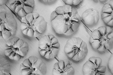 black and white photo of fresh garlic bulbs on a wooden background 