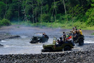 Yogyakarta, Endonezya - 19 Haziran 2022: Nehirde giden off-road jipleri. Endonezya 'nın doğal arazisinde 4x4 off-road araba macerası.