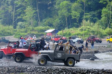 Yogyakarta, Endonezya - 19 Haziran 2022: Nehirde giden off-road jipleri. Endonezya 'nın doğal arazisinde 4x4 off-road araba macerası.