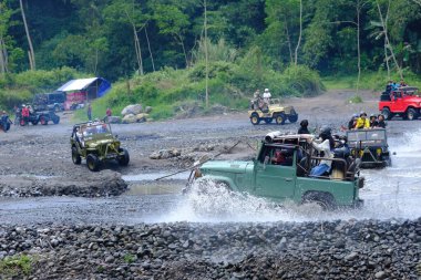 Yogyakarta, Endonezya - 19 Haziran 2022: Nehirde giden off-road jipleri. Endonezya 'nın doğal arazisinde 4x4 off-road araba macerası.