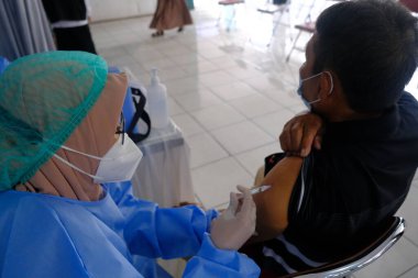 Yogya, Endonezya - 2 Eylül 2021: Yogyakarta 'da Covid-19 aşısı. Doktor aşıyı hastaya enjekte ediyor. - Ne? Bu aşı yaşlı, sağlıklı ve genç grupları hedef alıyor.