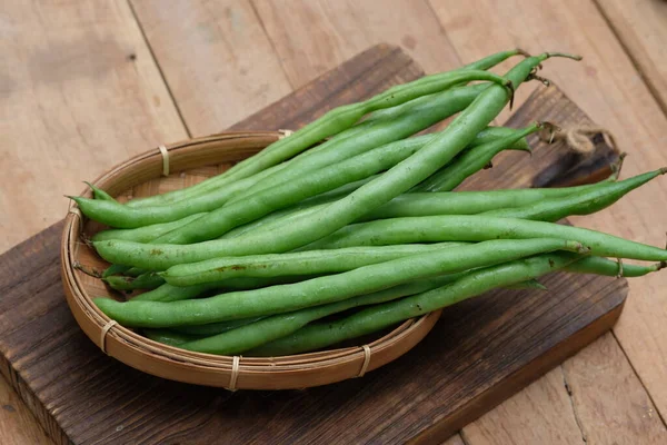 Green beans are known by many common names, including French beans, string beans, and snap beans or simply snaps on woven bamboo container