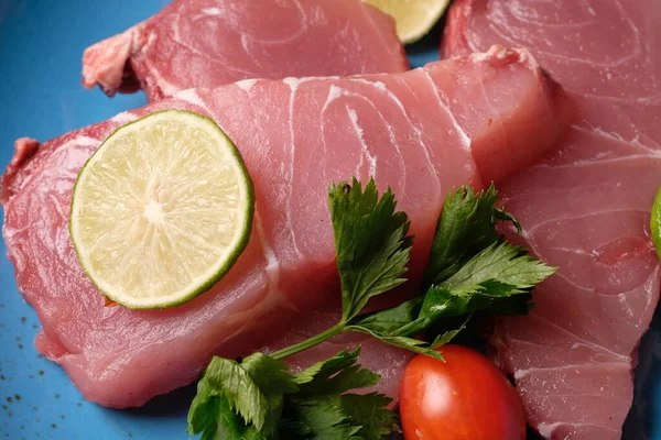 Limonlu çiğ balık filetosu ve mavi tabakta domates.
