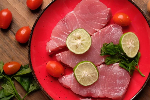 Limonlu çiğ balık filetosu ve kırmızı tabakta domates.