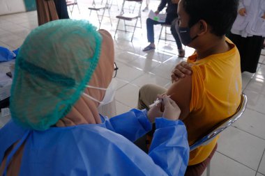 Yogya, Endonezya - 2 Eylül 2021: Yogyakarta 'da Covid-19 aşısı. Doktor aşıyı hastaya enjekte ediyor. - Ne? Bu aşı yaşlı, sağlıklı ve genç grupları hedef alıyor.