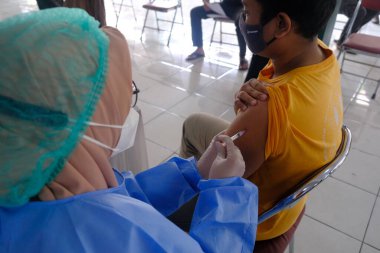 Yogya, Endonezya - 2 Eylül 2021: Yogyakarta 'da Covid-19 aşısı. Doktor aşıyı hastaya enjekte ediyor. - Ne? Bu aşı yaşlı, sağlıklı ve genç grupları hedef almaktadır..