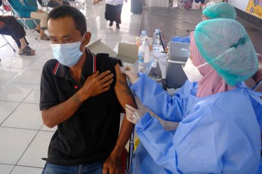 Yogya, Endonezya - 2 Eylül 2021: Yogyakarta 'da Covid-19 aşısı. Doktor aşıyı hastaya enjekte ediyor. - Ne? Bu aşı yaşlı, sağlıklı ve genç grupları hedef almaktadır..
