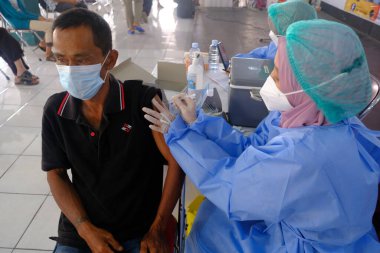 Yogya, Endonezya - 2 Eylül 2021: Yogyakarta 'da Covid-19 aşısı. Doktor aşıyı hastaya enjekte ediyor. - Ne? Bu aşı yaşlı, sağlıklı ve genç grupları hedef almaktadır..
