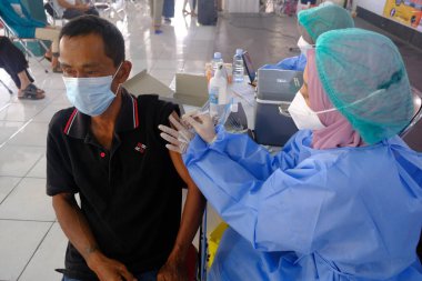 Yogya, Endonezya - 2 Eylül 2021: Yogyakarta 'da Covid-19 aşısı. Doktor aşıyı hastaya enjekte ediyor. - Ne? Bu aşı yaşlı, sağlıklı ve genç grupları hedef almaktadır..