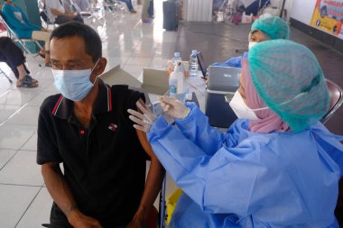 Yogya, Endonezya - 2 Eylül 2021: Yogyakarta 'da Covid-19 aşısı. Doktor aşıyı hastaya enjekte ediyor. - Ne? Bu aşı yaşlı, sağlıklı ve genç grupları hedef almaktadır..
