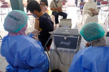 Yogya, Endonezya - 2 Eylül 2021: Yogyakarta 'da Covid-19 aşısı. Doktor aşıyı hastaya enjekte ediyor. - Ne? Bu aşı yaşlı, sağlıklı ve genç grupları hedef almaktadır..