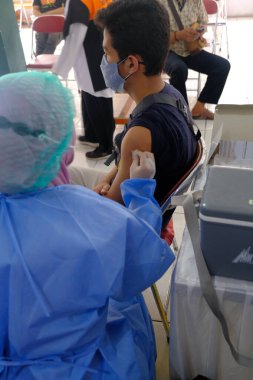 Yogya, Endonezya - 2 Eylül 2021: Yogyakarta 'da Covid-19 aşısı. Doktor aşıyı hastaya enjekte ediyor. - Ne? Bu aşı yaşlı, sağlıklı ve genç grupları hedef almaktadır..